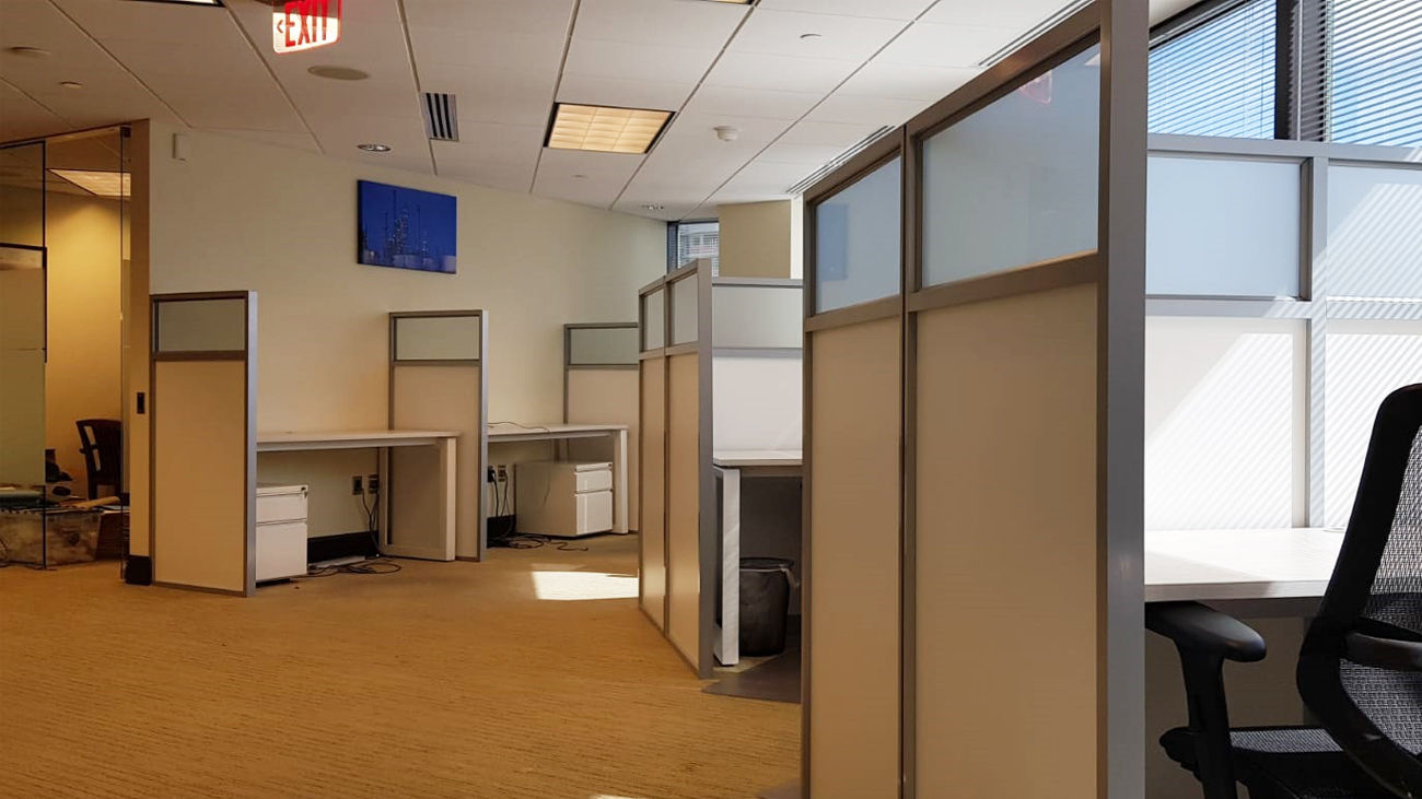 A table & a chair in a cubicle wall